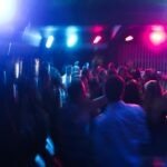 Vibrant nightclub scene with blurred dancing crowd and colorful lights.