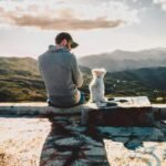 man sitting beside dog